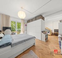 Hálószoba egy kétszobás lakásban fa dekoros padlóval, nagy ággyal és tárolóhelyekkel.