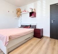 Hálószoba családi házban rózsaszín ággyal és fa dekorációjú padlóval.