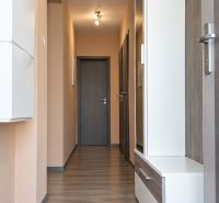Folyosó egy családi házban fa mintázatú padlóval és világos falakkal.