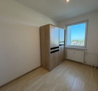 Szoba egy háromszobás lakásban, fa dekorációjú padlóval és kilátással az ablakból.