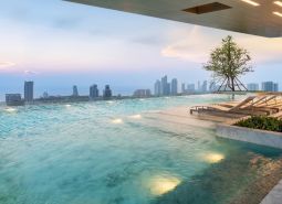 Medence napozóágyakkal és kilátással Pattaya város panorámájára, lakásépítések.