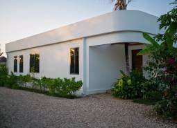 Házak építése Paje-ben, Unguja déli régiójában, zöld területtel a fehér épület körül.