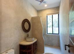 Fürdőszoba mosdóval, kerek szőnyeggel és ventilátorral. Házépítés.