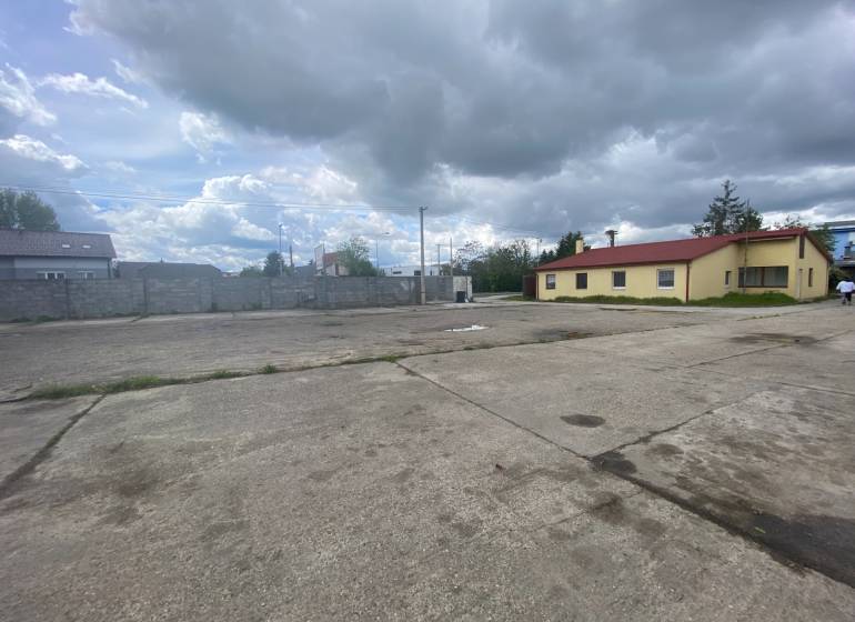 Na ulici Dvojkrížna, betónová plocha pri výrobnej budove pod zamračenou oblohou.