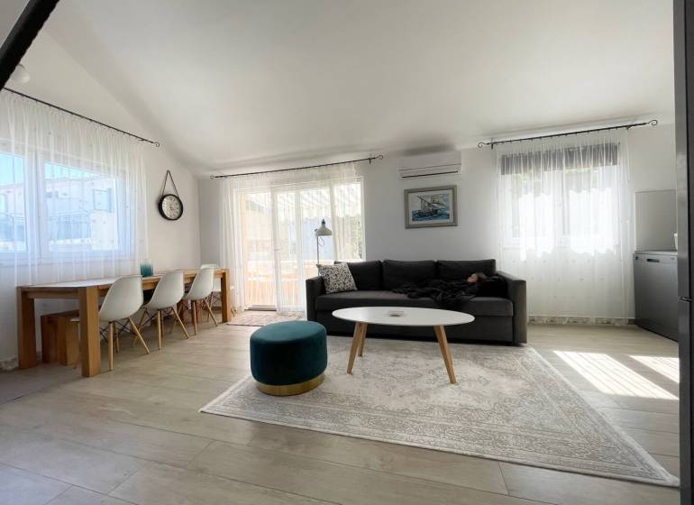 Tágas nappali rekreációs apartman kényelmes ülőgarnitúrával és étkezőasztallal.