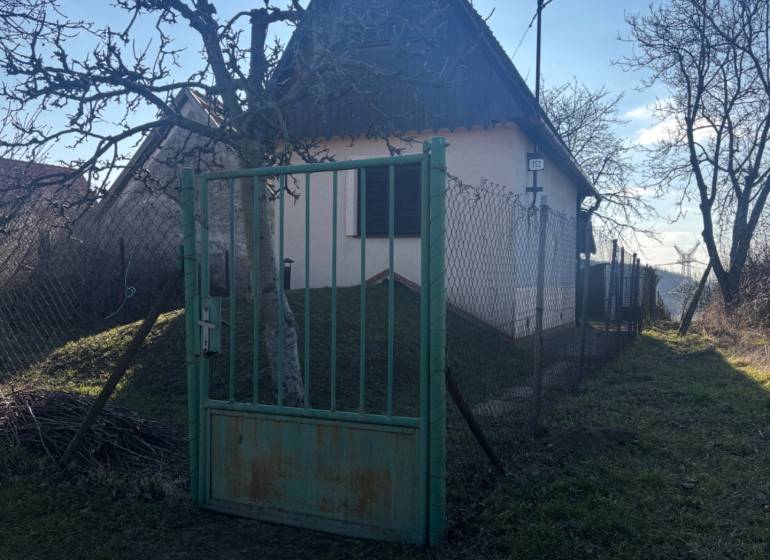 Kis házikó fákkal körülvéve, bekerített kert, ideális üdülőteleknek.