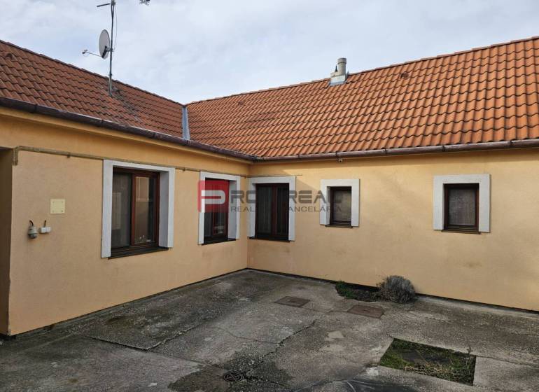 A Pezinkben, a Nap utcában található családi ház udvara betonburkolattal és narancssárga homlokzattal.