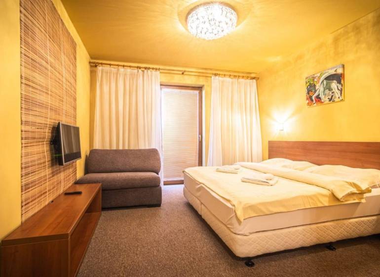 Hálószoba nyaraló apartmanban franciaággyal, kanapéval és televízióval.