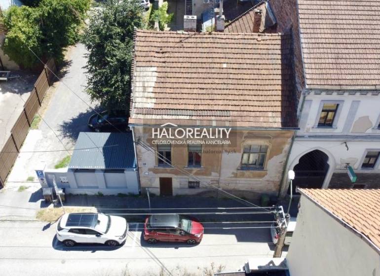 Családi ház Rimaszombatban régi homlokzattal és az utcán parkoló autókkal.