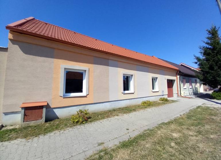Családi ház Trakoviceben narancssárga homlokzattal és piros tetővel.