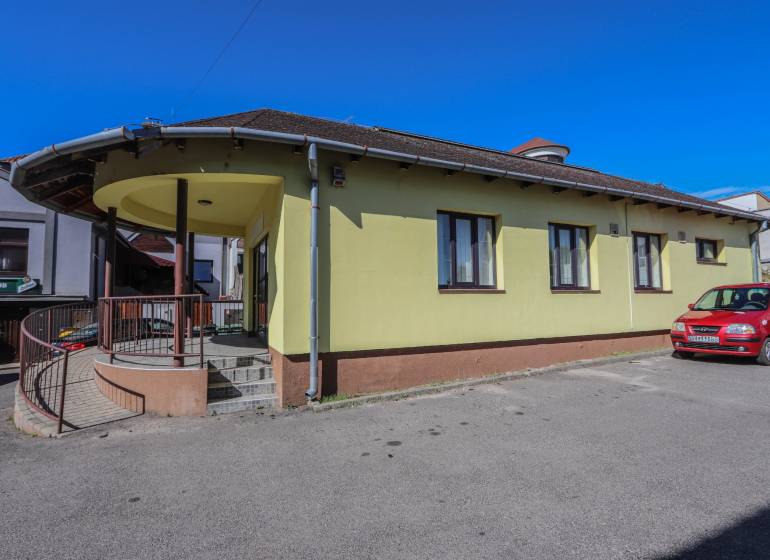 Sárga épület parkolóval és autóval a Szlovák Nemzeti Felkelés utcában, Vrbovéban.