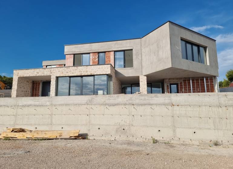 Egy villa külseje Vodice-ben modern ablakokkal és nyers betonnal.