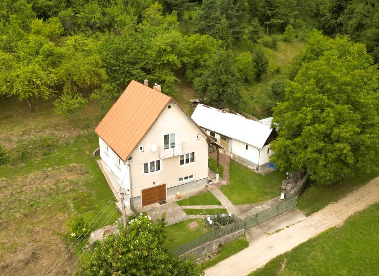 Családi ház Papradnóban, füves telekkel és fákkal körülvéve, megközelítési úttal.