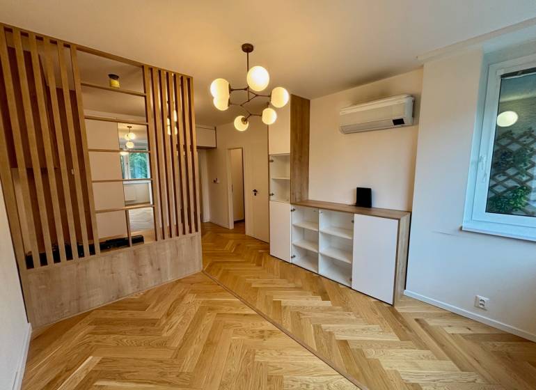 2 szobás lakás belső tere fa padlóval, válaszfallal és modern világítással.
