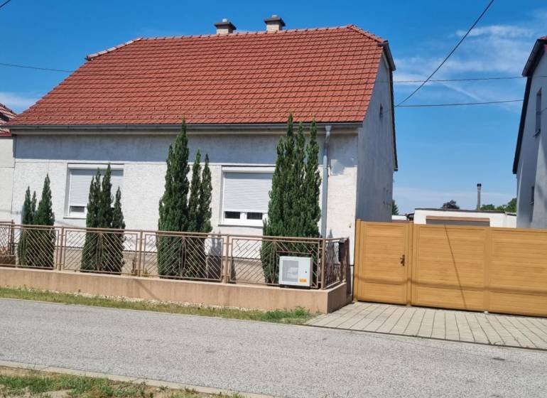 Családi ház a Písniky utcában, Malackán, fehér homlokzat, piros tető, tujafák a kerítésnél.