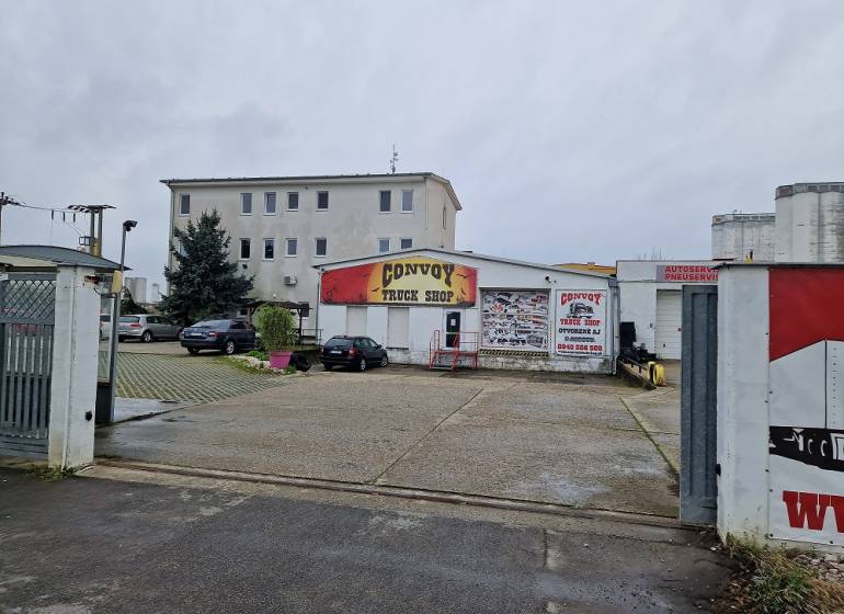 Konvoj Kamion Shop épület a Šamorínska utcában, raktár és csarnokok mellett parkoló autókkal körülvéve.