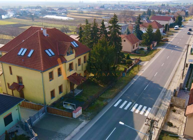 Egy épület a Chrabrany utcában, Topoľčanyban, házakkal és fákkal körülvéve, a főút mellett.