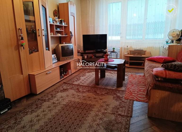 Nappali egy kétszobás lakásban alapvető berendezéssel és szőnyeggel a padlón.