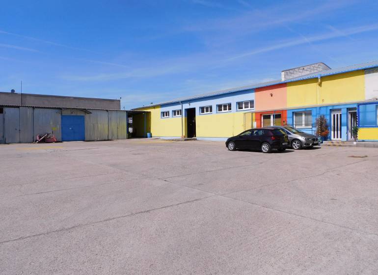 Színes raktár- és csarnoképületek parkolóval és autókkal Trnavában.