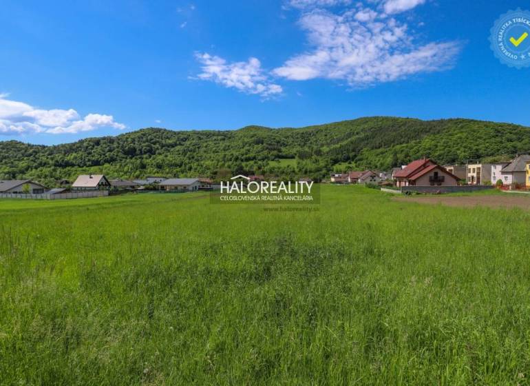 Zöldterület és panoráma Udičában, lakóterületek házakkal és erdős dombokkal a háttérben.