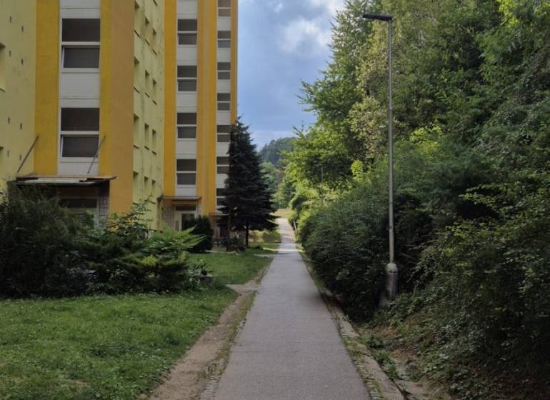 Sárga lakóház a Moszkva utcában Besztercebányán, a járda és a zöldterület mellett.