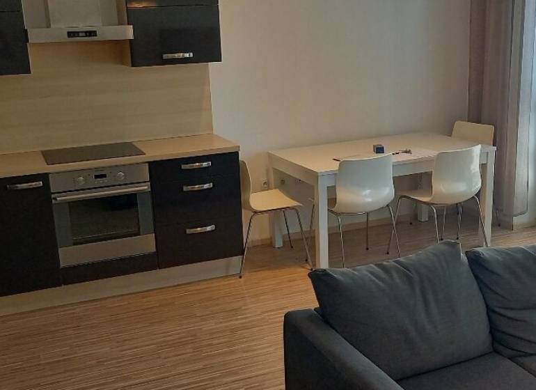 Konyha és nappali egy kétszobás lakásban modern konyhabútorral és étkezőasztallal.