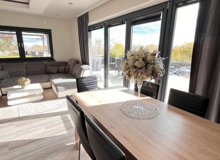 Családi ház nappalija fa dekorációjú padlóval és kényelmes ülőgarnitúrával.