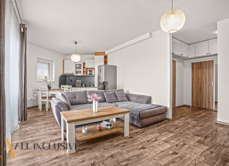 Nappali egy kétszobás lakásban kanapéval és fa dekorációjú padlóval.