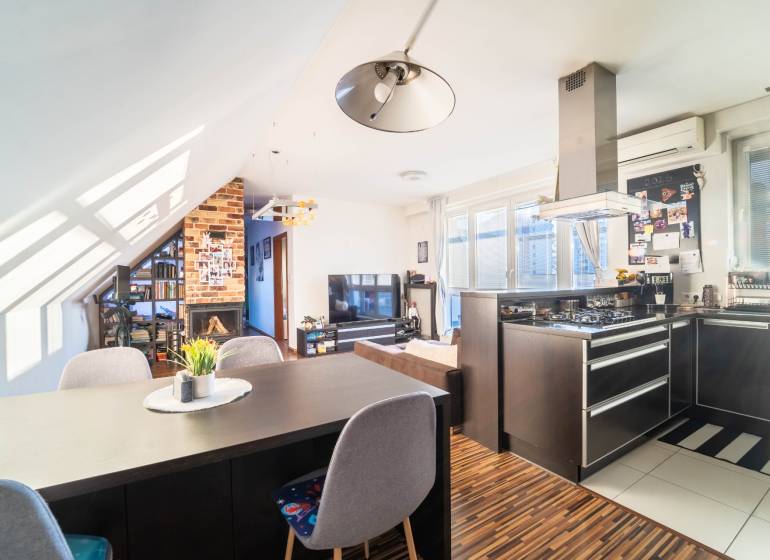 Konyha televízióval, kandallóval és fa hatású padlóval egy kétszobás lakásban.