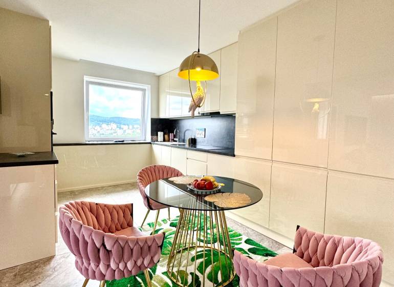 Étkező sarok üveg asztallal és rózsaszín székekkel egy háromszobás lakásban.
