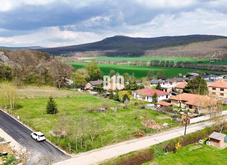 Telkek - lakóövezet Jelenecen, természet által körülvéve és családi házakkal, háttérben erdős dombokkal.