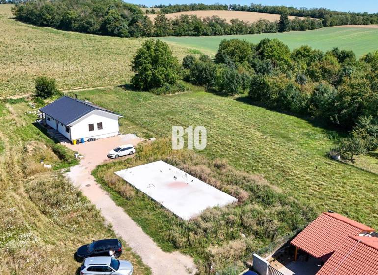 Telek kilátás lakóhely céljára Csallóközben, amely magában foglalja a házat, a zöldterületet és az autókat.