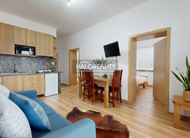 Nappali egy háromszobás lakásban, fa hatású padlóval és kényelmes ülőgarnitúrával.