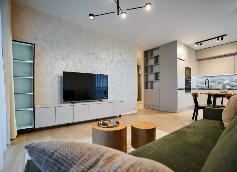 Nappali egy kétszobás lakásban fa dekor padlóval és modern konyhával.