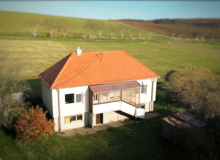 Családi ház Dobra Vodán ferde tetővel, zölddel és rétekkel körülvéve.