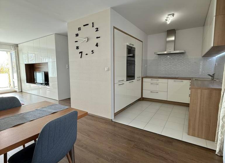 Étkező tér egy 4 szobás lakásban fa mintázatú padlóval és háttérben a konyhával.