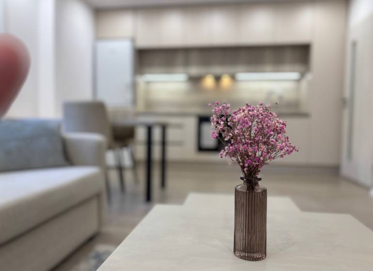 Nappali konyhával és virágokkal az asztalon egy kétszobás lakásban.