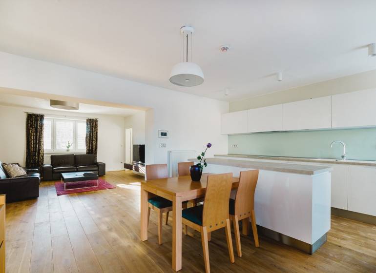 Konyha és nappali családi házban, fa hatású padlóval és világos bútorokkal.