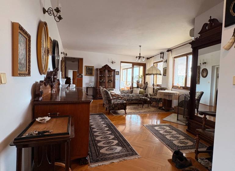 Öt vagy több szobás lakás fa dekor padlóval, klasszikus bútorokkal és szőnyegekkel.