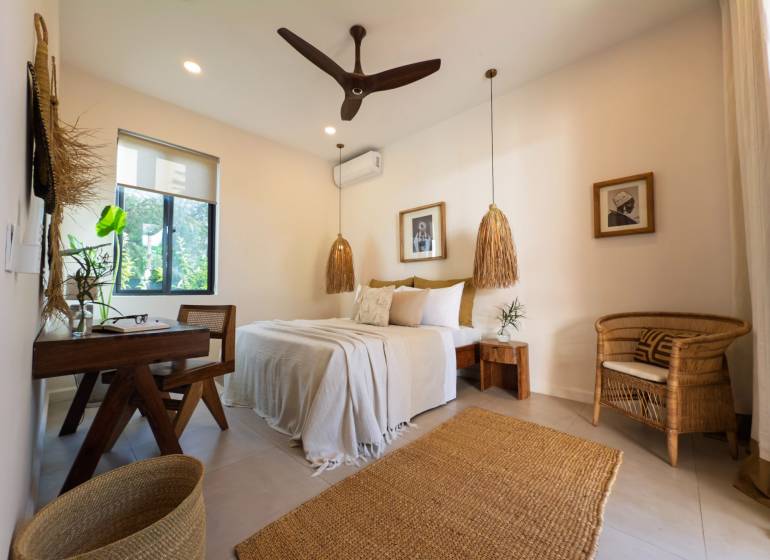 Világos hálószoba függőlámpákkal és fonott bútorokkal egy családi házban.