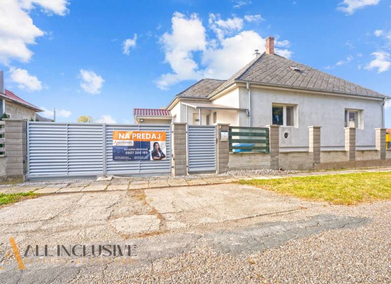 Eladó családi ház Nagycsalomján, fehér homlokzati burkolat, széles kapu.