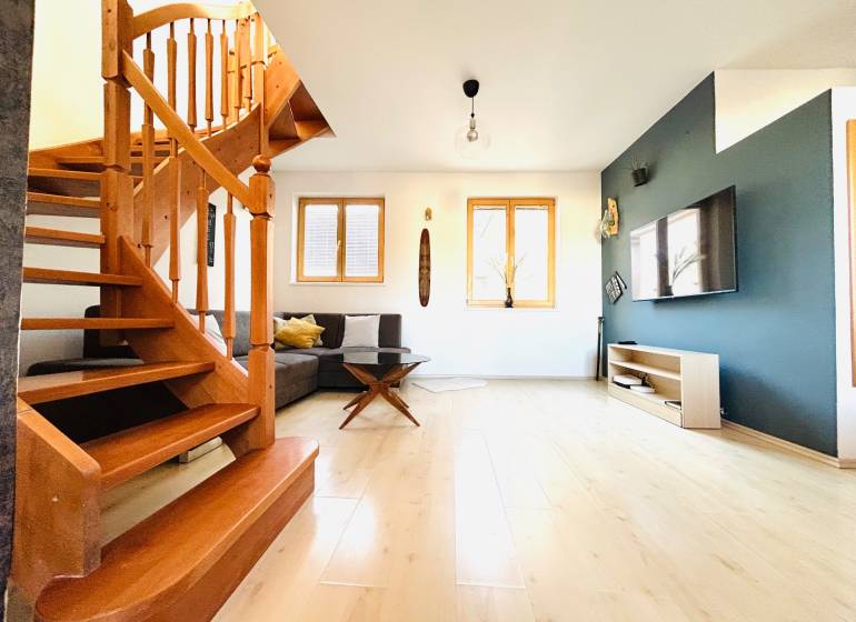 Nappali szoba fa lépcsőkkel, fa dekor padlóval és televízióval egy kétszobás lakásban.