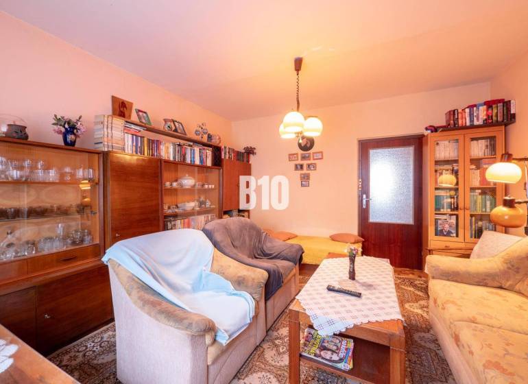 Nappali egy kétszobás lakásban kanapékkal, könyvespolccal és fa dekorációjú padlóval.