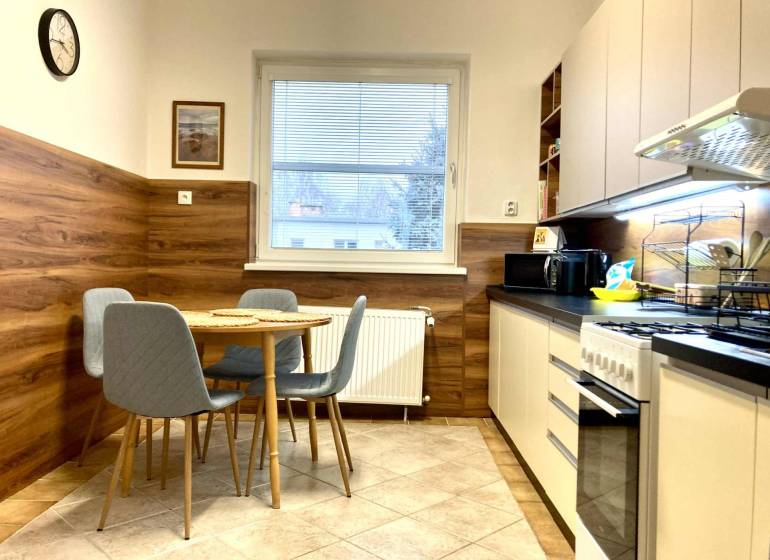 Konyha egy háromszobás lakásban étkezőasztallal, fa dekorációjú padló.