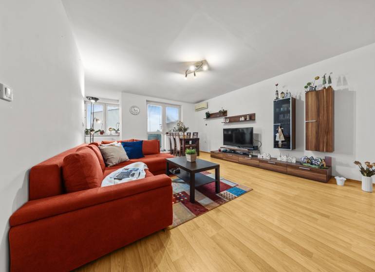 Nappali egy kétszobás lakásban, fa dekoros padlóval, kanapéval és televízióval.