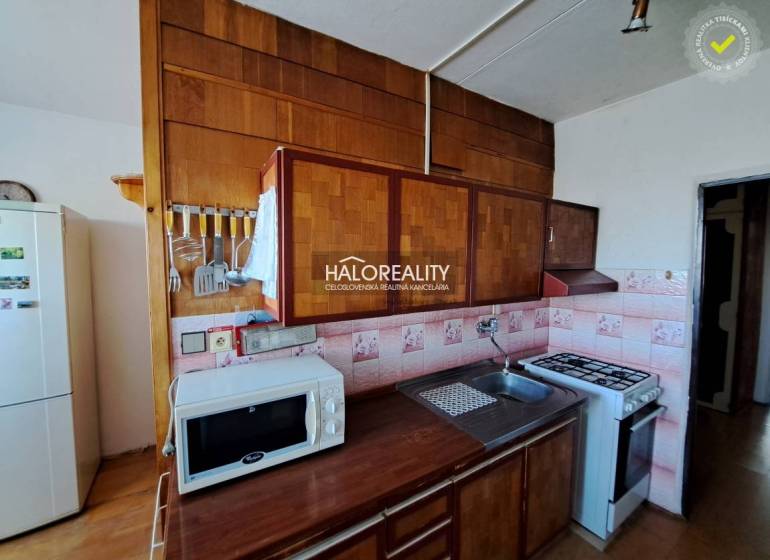 Nappali egy háromszobás lakásban kanapékkal, fa dekor padlóval és nagy ablakokkal.