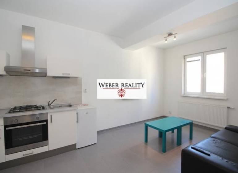 Konyha egy kétszobás lakásban szürke padlóval, konyhabútorral és ülőhellyel.