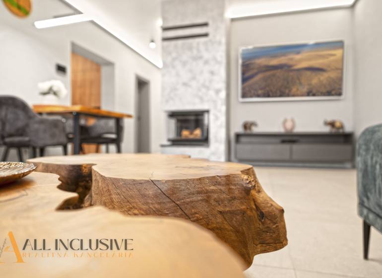 Nappali egy családi házban kandallóval, dekoratív faasztallal és kényelmes ülőgarnitúrával.