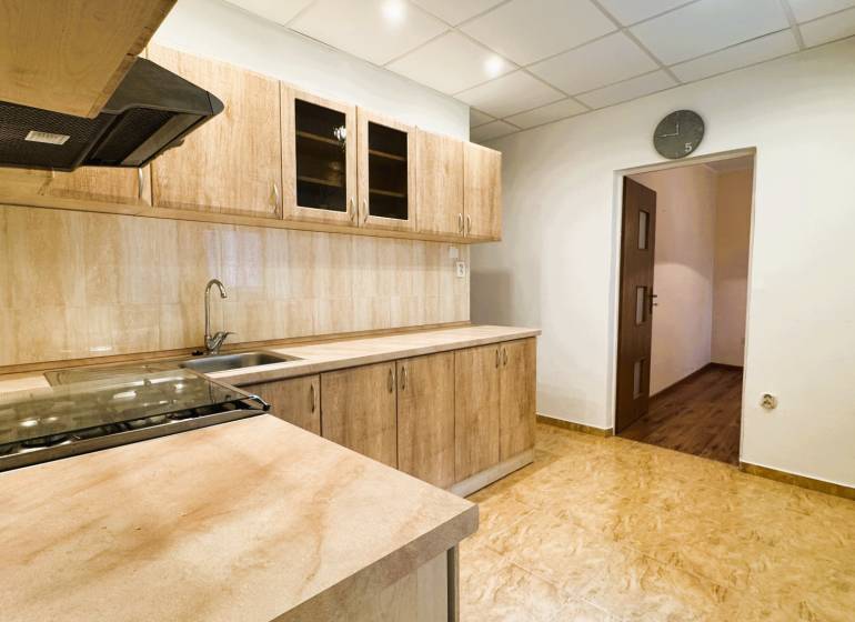 Konyha egy háromszobás lakásban, fa dekorációjú konyhabútorral és padlóval.