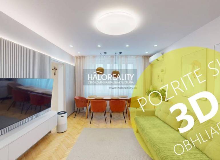 Nappali egy háromszobás lakásban, televízióval, kanapéval és fa padlódekorációval.